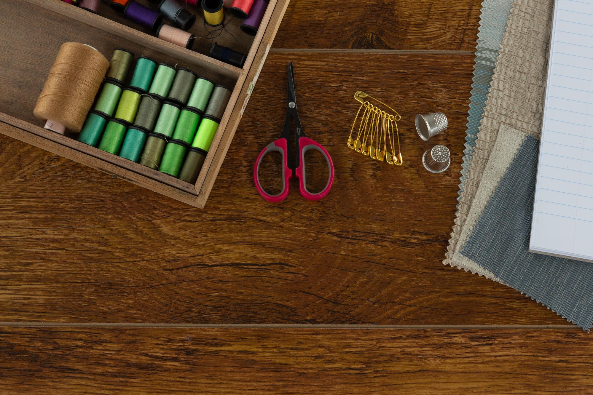 assorted embroidery threads and needles on wooden table